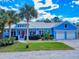 Charming blue home with well-manicured lawn, palm trees and two-car garage at 905 Maple St, New Smyrna Beach, FL 32169