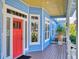 Inviting front porch featuring a bright red door, coastal accents, and an abundance of natural light at 905 Maple St, New Smyrna Beach, FL 32169