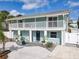 Two-story duplex with a light blue exterior, white columns, a balcony, and a well-manicured front yard at 910 Maple St # A & B, New Smyrna Beach, FL 32169