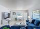 Bright living room featuring a comfortable blue sofa, white floors, and a small desk by the window at 910 Maple St # A & B, New Smyrna Beach, FL 32169