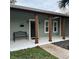 Covered front porch with stained columns and a black front door, with landscaping at 956 Tall Pine Dr, Port Orange, FL 32127