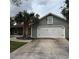 Exterior view of a home with a white two-car garage door and palm trees in front of the home at 956 Tall Pine Dr, Port Orange, FL 32127