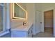 Bright bathroom features a vanity with white countertop and a large, backlit mirror; leads to walk-in closet at 1350 Scarlett Trl, New Smyrna Beach, FL 32168