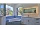 Bright bathroom features a soaking tub with blue tile surround and a large, backlit mirror over the vanity at 1350 Scarlett Trl, New Smyrna Beach, FL 32168