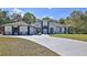 Front exterior featuring a circular paved driveway, well-kept lawn, lush landscaping, and white stucco at 1350 Scarlett Trl, New Smyrna Beach, FL 32168