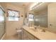 Well-lit bathroom with vanity, sink, toilet, mirror, and a glass-enclosed shower and floral patterned window at 15 Katrinas Dr, Ormond Beach, FL 32174