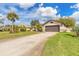 View of the home and extra long driveway, surrounded by tropical landscaping and lush green lawns at 15 Katrinas Dr, Ormond Beach, FL 32174
