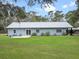 A backyard features a well-maintained lawn, mature landscaping, and patio furniture at 1715 Fern Park Dr, Port Orange, FL 32128