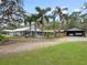 Sprawling home featuring palm trees, a pool, a covered outdoor space, a carport and a well-manicured green lawn at 1715 Fern Park Dr, Port Orange, FL 32128
