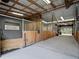 A horse barn interior featuring multiple stalls, metal bars, and concrete flooring at 1715 Fern Park Dr, Port Orange, FL 32128