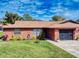 Inviting red brick home with manicured lawn, vibrant plants, and a charming screened garage at 1818 Enterprise Ave # B, New Smyrna Beach, FL 32168