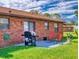 Cozy outdoor patio with a brick exterior, well-maintained lawn, and grill for outdoor cooking at 1818 Enterprise Ave # B, New Smyrna Beach, FL 32168