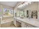 A bathroom with double sinks, a large mirror, a soaking tub, and a tiled shower with glass door at 1880 1St Ave, Deland, FL 32724