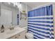 Bright bathroom features a vanity with a sink and a shower with a blue and white striped curtain at 1880 1St Ave, Deland, FL 32724