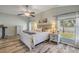 Sun-drenched main bedroom featuring wood floors, a ceiling fan, and windows overlooking the lush backyard at 1880 1St Ave, Deland, FL 32724