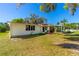 Exterior of a white home with a green house nearby and a grassy lawn at 191 Howes St, Oak Hill, FL 32759