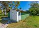 A detached green painted garage with a white storage room addition on a well-maintained lawn at 191 Howes St, Oak Hill, FL 32759