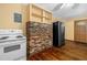 Kitchen featuring a vintage stove, refrigerator, and a brick accent wall with shelving at 191 Howes St, Oak Hill, FL 32759