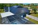 Aerial view of a screened-in pool and metal roof with solar panels on a private home with a fenced-in yard at 1948 Spruce Creek Lndg, Port Orange, FL 32128