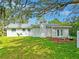 A view of the backyard showing the house, lawn, seating area, and mature trees at 20 Warwick Ave, Ormond Beach, FL 32174