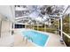 Enjoy the sun in this screened-in pool with clear blue water and a patio surrounded by mature trees at 2307 Needle Palm Dr, Edgewater, FL 32141