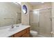 Well-lit bathroom featuring white sink, toilet, shower with glass doors, and an eye-catching mirror at 2333 Southern Pines Pl, Deland, FL 32724
