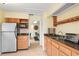 Charming kitchenette with wood cabinets, stainless fridge, dark countertops, and view into game room at 2333 Southern Pines Pl, Deland, FL 32724