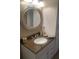 Charming bathroom features a granite counter, round mirror, and white cabinets for storage at 2409 Victory Palm Dr, Edgewater, FL 32141