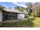 Back of house with a screened-in porch and outdoor patio spaces, set against a backdrop of mature trees and green lawn at 2576 Shilo Glynn Ln, New Smyrna Beach, FL 32168