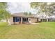 Backyard featuring a well-maintained lawn, mature trees, and patio and a tan home exterior at 2626 Turnbull Estates Dr, New Smyrna Beach, FL 32168
