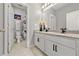 Bathroom featuring double sinks with granite countertops, white cabinets, and tile flooring, offering a clean and functional space at 2951 Meleto Blvd, New Smyrna Beach, FL 32168