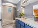 Bathroom features a tub with shower, blue vanity and sink, and an arched window at 3403 Kumquat Dr, Edgewater, FL 32141