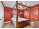Bedroom features a wooden four-poster bed, ceiling fan, and rich red walls and wood-look floors at 3403 Kumquat Dr, Edgewater, FL 32141