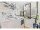 Well-lit laundry room features a washer, dryer, water heater, and shelving at 5300 S Atlantic Ave # 3-301, New Smyrna Beach, FL 32169