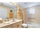 Bright bathroom featuring a tub with shower, neutral tile, and a vanity with ample countertop space at 5300 S Atlantic Ave # 7-307, New Smyrna Beach, FL 32169