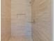 Walk-in shower featuring beige marble-look tiling and a built-in shelf at 5424 Frederick Lake Dr, Port Orange, FL 32128