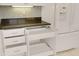 Kitchen area with white cabinets, stone countertop and stainless steel fridge at 55 Bay Harbour Dr, Ponce Inlet, FL 32127