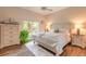 Sun-filled bedroom features wood-look flooring, area rug, and a plant near the window at 6049 Sabal Hammock Cir, Port Orange, FL 32128