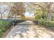 Long driveway secured with a gate, leading to a home surrounded by mature trees and landscaping at 6049 Sabal Hammock Cir, Port Orange, FL 32128