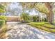 Gated driveway offers privacy leading to a well-maintained home with a lush front lawn and mature palm trees at 6049 Sabal Hammock Cir, Port Orange, FL 32128