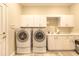 Well-equipped laundry room with white cabinets, a sink, and modern washing machines at 6049 Sabal Hammock Cir, Port Orange, FL 32128