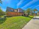 Charming two-story townhouse with a wood fence, lush lawn, and a view of palm trees against a clear blue sky at 61 Cedar Dunes Dr, New Smyrna Beach, FL 32169