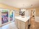 Kitchen featuring eat-in island, tile floors, access to the fenced patio, and a laundry closet at 61 Cedar Dunes Dr, New Smyrna Beach, FL 32169