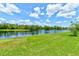 Picturesque lake view with green grass leading to the water's edge beneath a bright sky, capturing a tranquil outdoor atmosphere at 612 Mount Olympus Blvd, New Smyrna Beach, FL 32168