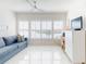 Bright living room with a blue sofa, white shutters, and a TV on a dresser at 6584 Engram Rd # 405, New Smyrna Beach, FL 32169