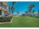 Exterior of condo building showing manicured lawn, palm trees, and easy access to beach and ocean at 701 S Atlantic Ave # 11, New Smyrna Beach, FL 32169