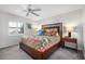 Bright bedroom featuring a patterned quilt bedspread, ceiling fan, and a window with shutter blinds at 701 S Atlantic Ave # Ut11, New Smyrna Beach, FL 32169