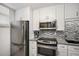 Modern kitchen featuring stainless steel appliances, granite countertops, and a mosaic tile backsplash at 701 S Atlantic Ave # 11, New Smyrna Beach, FL 32169
