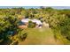 Aerial view of home with large lawn, lush trees, shed, and metal carport at 725 Ingham Rd, New Smyrna Beach, FL 32168