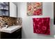 Bathroom vanity area featuring tile backsplash, modern lighting, and colorful art at 725 Ingham Rd, New Smyrna Beach, FL 32168